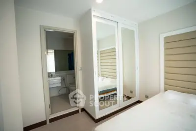 Modern bedroom with mirrored wardrobe and ensuite bathroom in a stylish apartment.