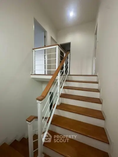 Modern staircase with wooden steps and sleek railing in a contemporary home.