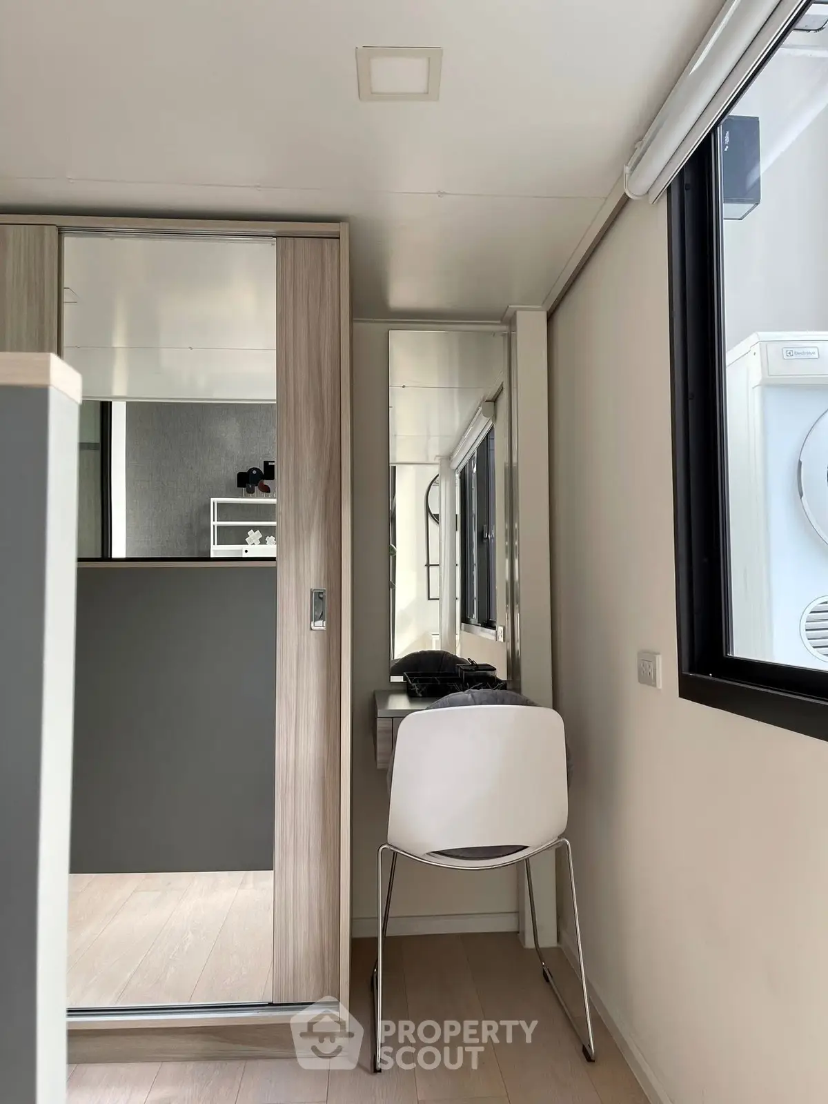 Modern compact study nook with sleek chair and mirrored closet in bright apartment.