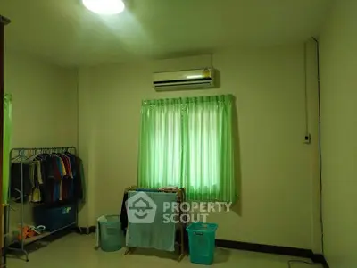 Cozy bedroom with air conditioning and natural light, featuring green curtains and organized storage space.