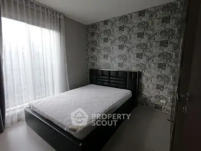 Modern bedroom with stylish wallpaper and large window for natural light.