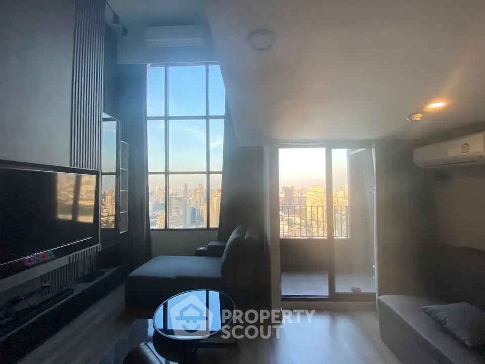 Modern living room with large windows offering stunning city views and a cozy seating area.