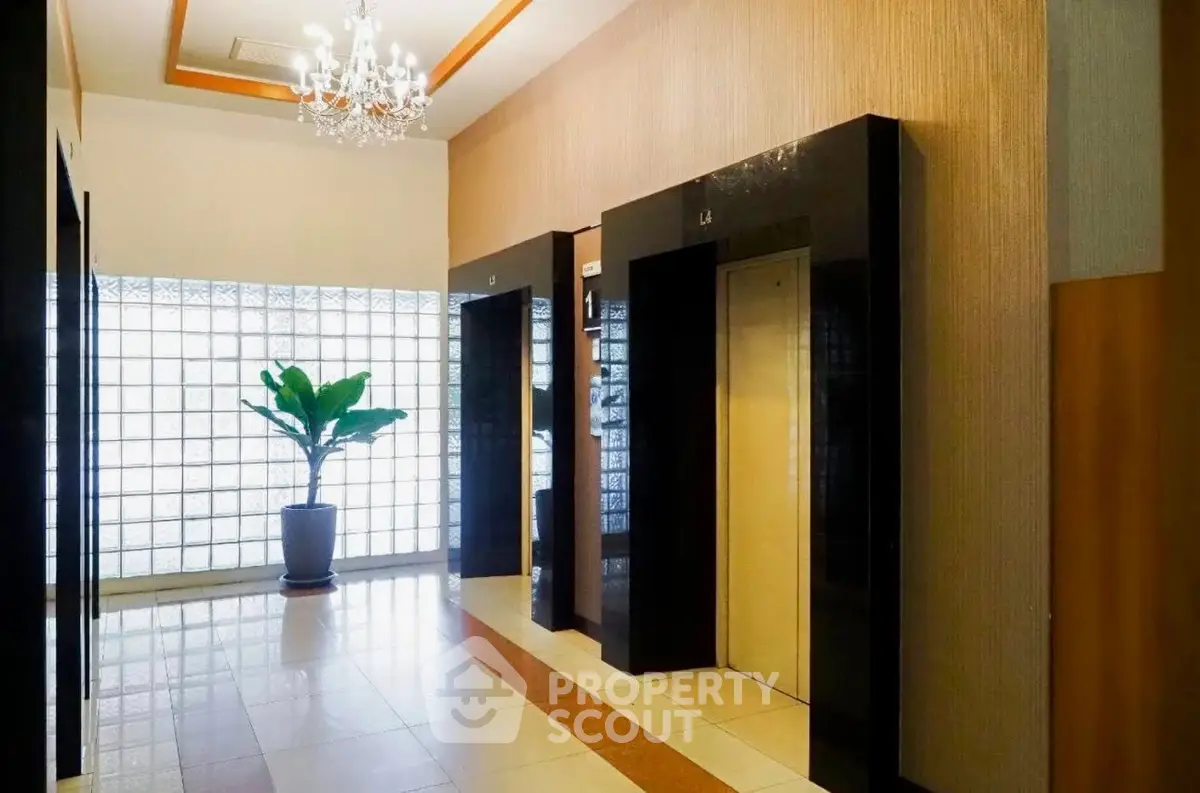 Elegant building lobby with modern elevators and stylish chandelier lighting.