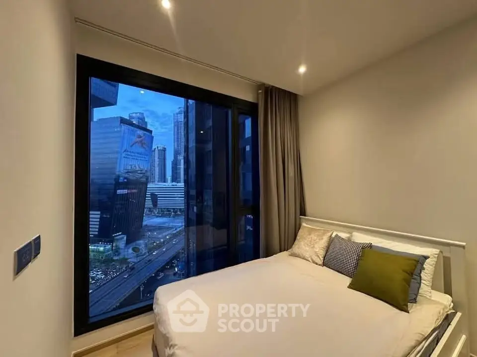 Modern bedroom with city view, featuring large window and cozy bed in urban apartment.