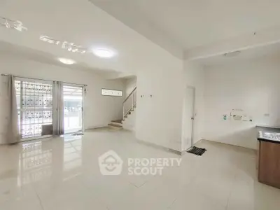 Spacious open-plan living area with modern staircase and natural light.