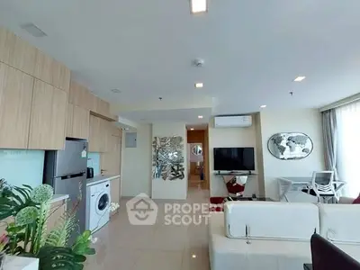 Modern open-plan living room with kitchen, featuring sleek appliances and stylish decor.