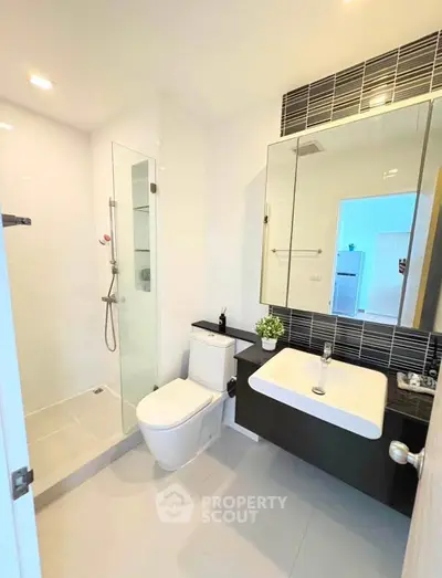 Modern bathroom with sleek fixtures and glass shower enclosure in a contemporary apartment.