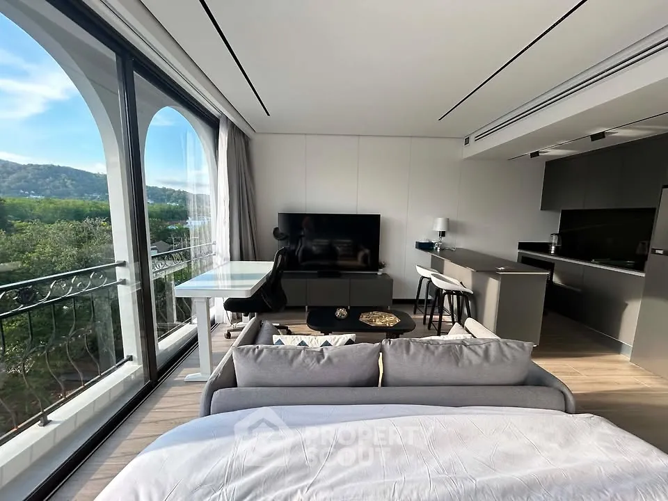 Modern studio apartment with open layout, large windows, and scenic view.