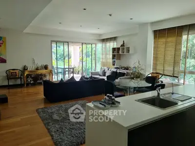Spacious living room with modern decor and large windows overlooking greenery.