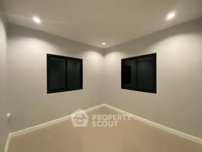 Minimalist empty room with tiled floor and two windows, ideal for customization.