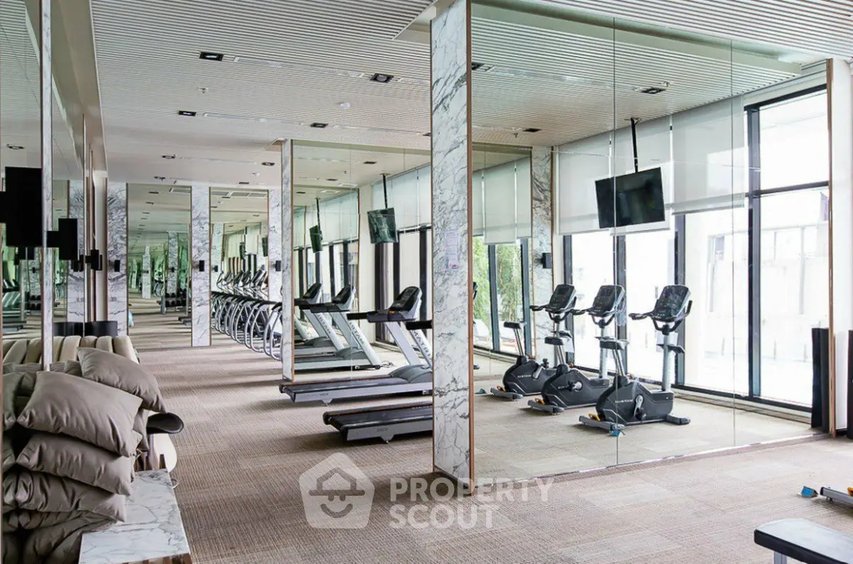 Luxurious gym with modern equipment and mirrored walls in upscale residential building.