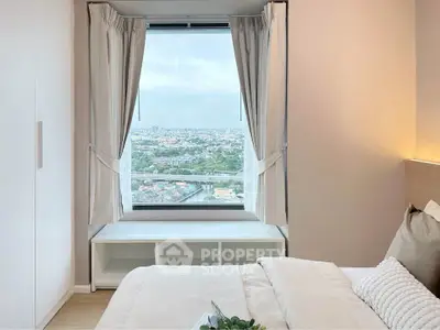 Cozy bedroom with stunning city view from large window, elegant decor and natural light.