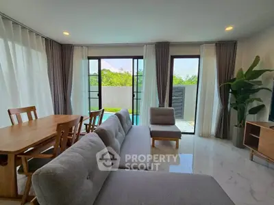 Spacious living room with modern furniture and pool view, perfect for relaxation and entertaining.