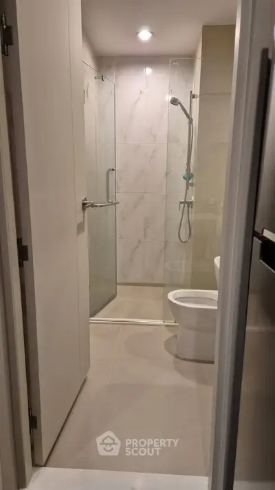 Modern bathroom with glass shower enclosure and sleek fixtures in a contemporary apartment.