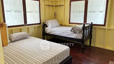 Cozy bedroom with two beds and large windows in a charming home.