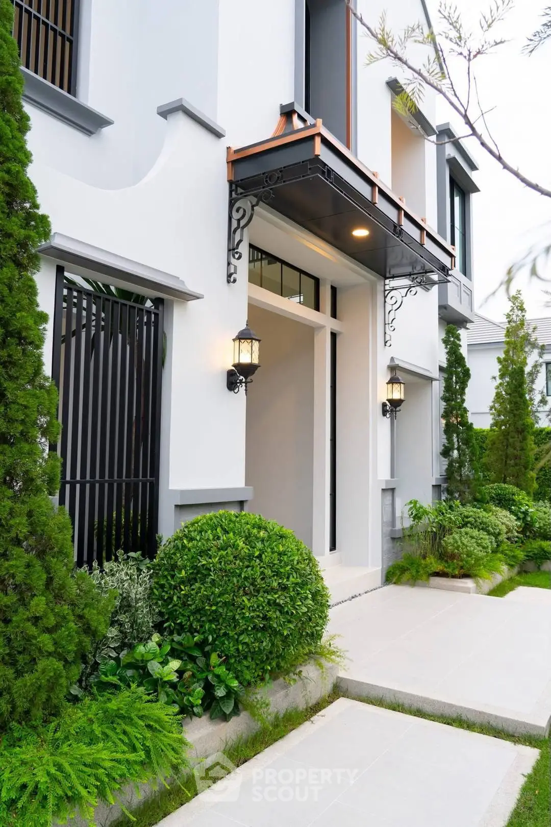 Elegant modern building exterior with lush greenery and stylish lighting fixtures.