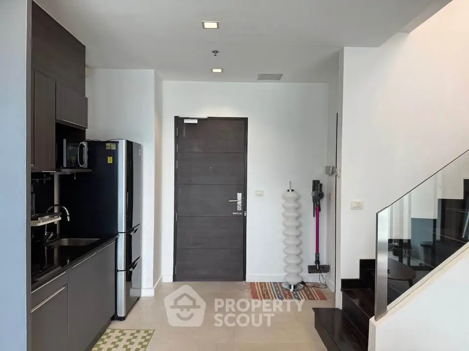 Modern kitchen with sleek appliances and staircase in stylish apartment