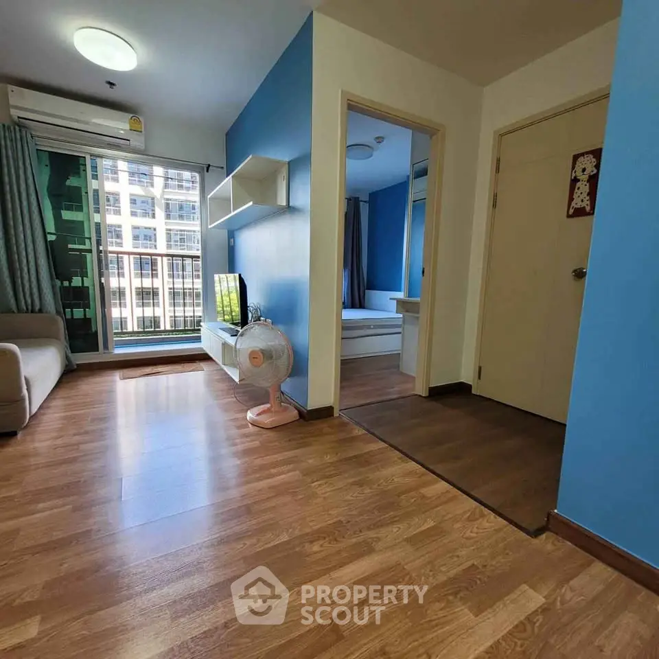 Modern apartment interior with blue accents, featuring a spacious living area and large windows.