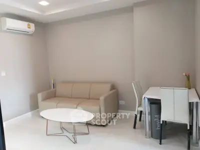 Modern living room with beige sofa, white table, and dining area in a stylish apartment.