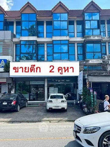 Commercial building exterior with glass facade and parking area in front, ideal for business opportunities.