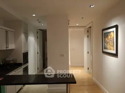 Modern apartment interior with sleek kitchen and hallway, featuring contemporary artwork on the wall.