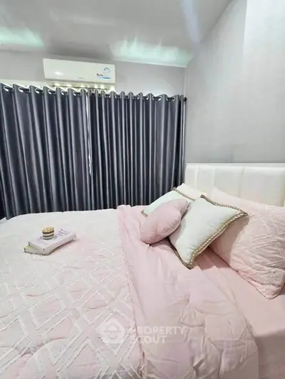 Cozy bedroom with elegant pink bedding and modern air conditioning, perfect for relaxation.
