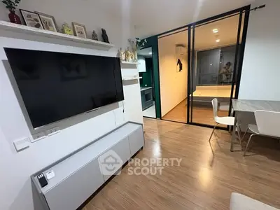 Modern living room with sleek TV setup and dining area, featuring sliding glass doors.