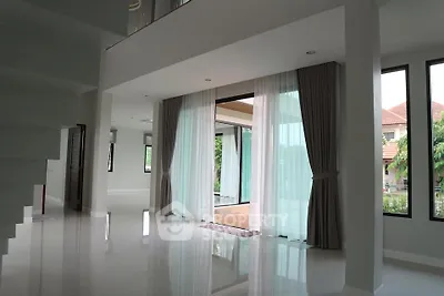 Spacious modern living area with large windows and elegant curtains