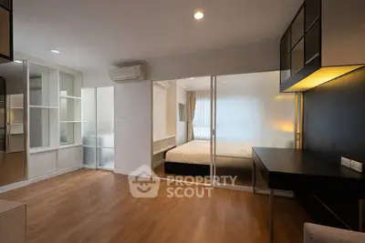 Modern bedroom with sliding glass doors and wooden flooring, featuring a cozy workspace and ample storage.