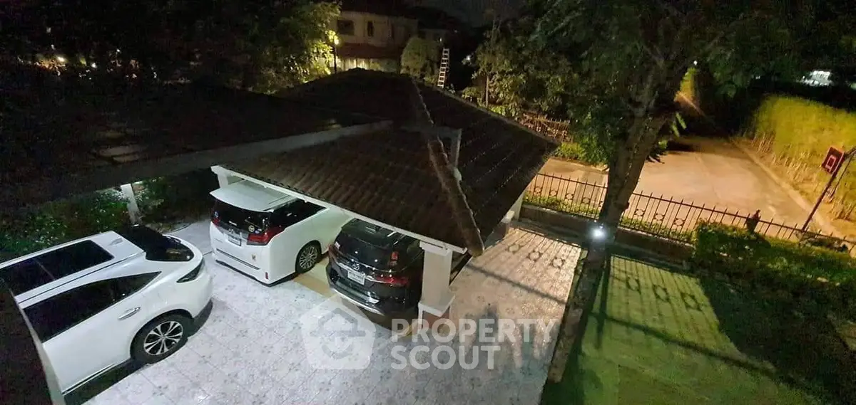 Spacious residential carport with tiled flooring and covered roof, accommodating multiple vehicles.