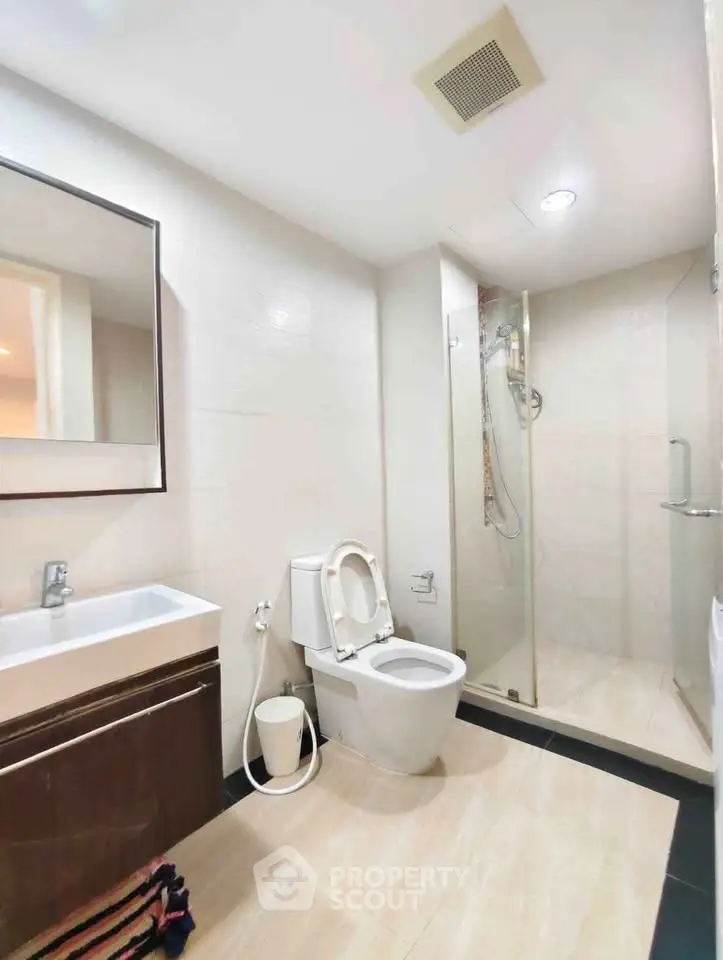 Modern bathroom with sleek fixtures and glass shower enclosure in a contemporary apartment.
