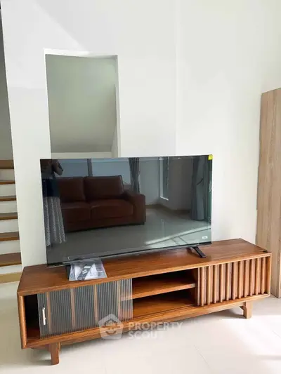 Modern living room with stylish wooden TV stand and sleek flat-screen TV