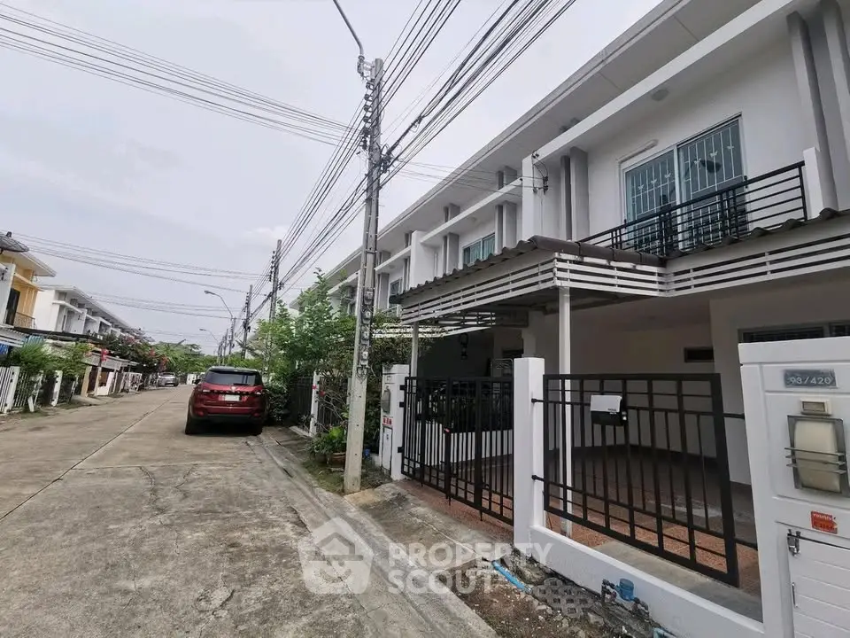 Modern townhouse exterior with gated entrance and driveway in suburban neighborhood.