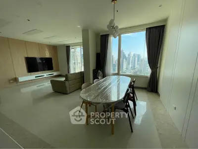 Spacious modern living room with city view, featuring elegant dining area and large TV setup.