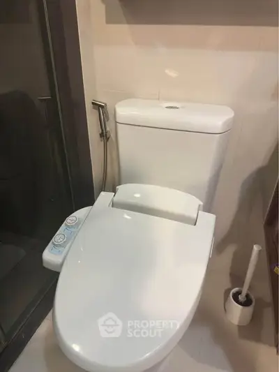 Modern bathroom with sleek toilet and bidet attachment, showcasing contemporary design and functionality.