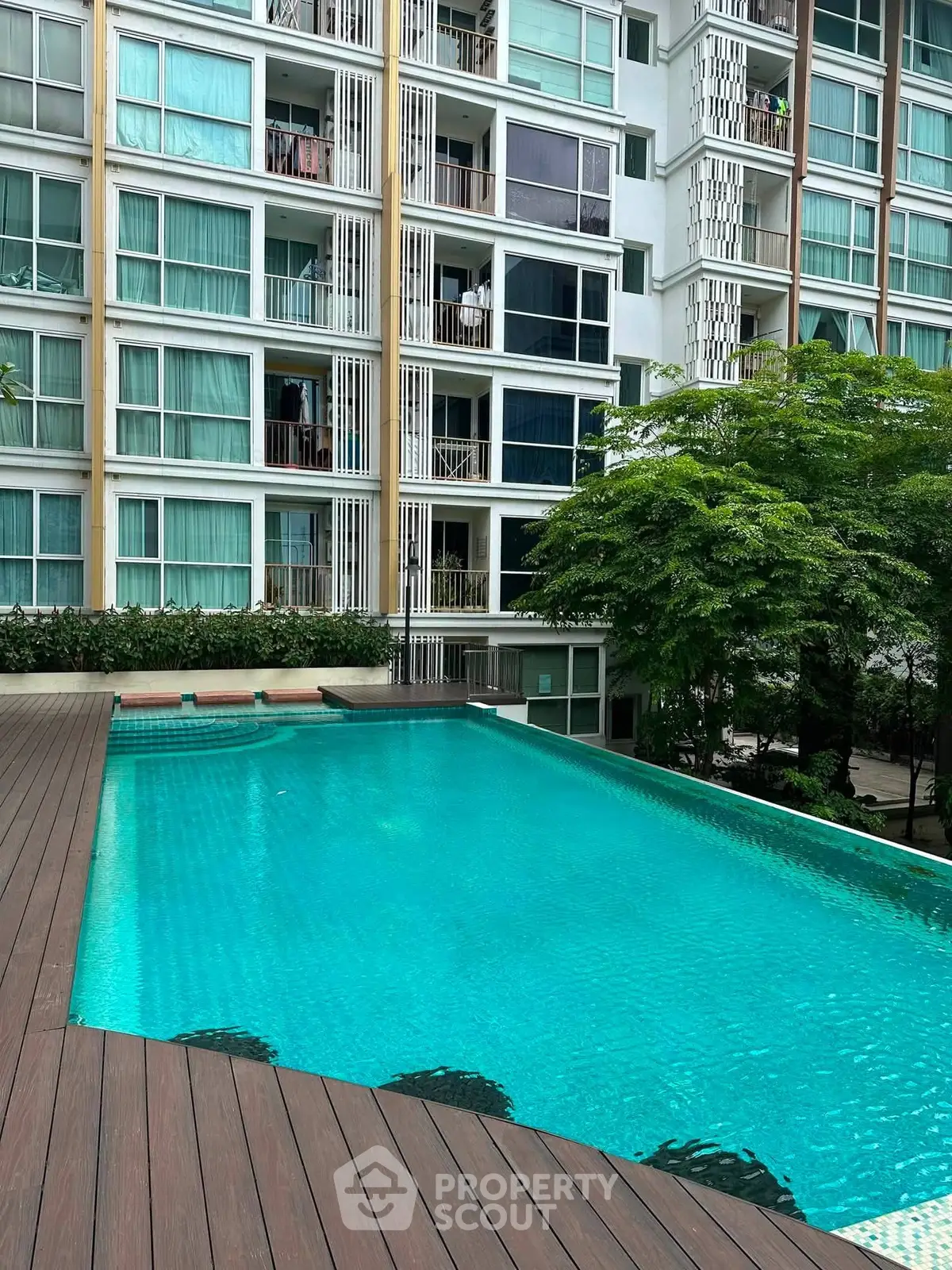 Modern apartment building with a refreshing outdoor pool and lush greenery, perfect for urban living.