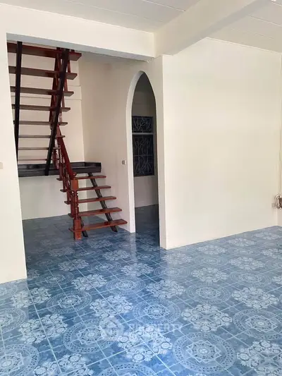 Charming interior with blue patterned tile flooring and wooden staircase, perfect for cozy living.