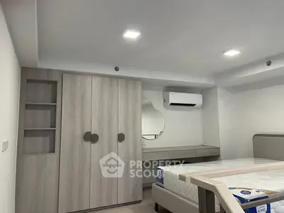 Modern bedroom with built-in wardrobe and air conditioning, featuring a stylish mirror and cozy bed setup.
