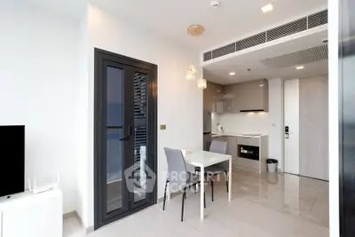 Modern apartment interior with open kitchen and dining area, featuring sleek design and contemporary lighting.