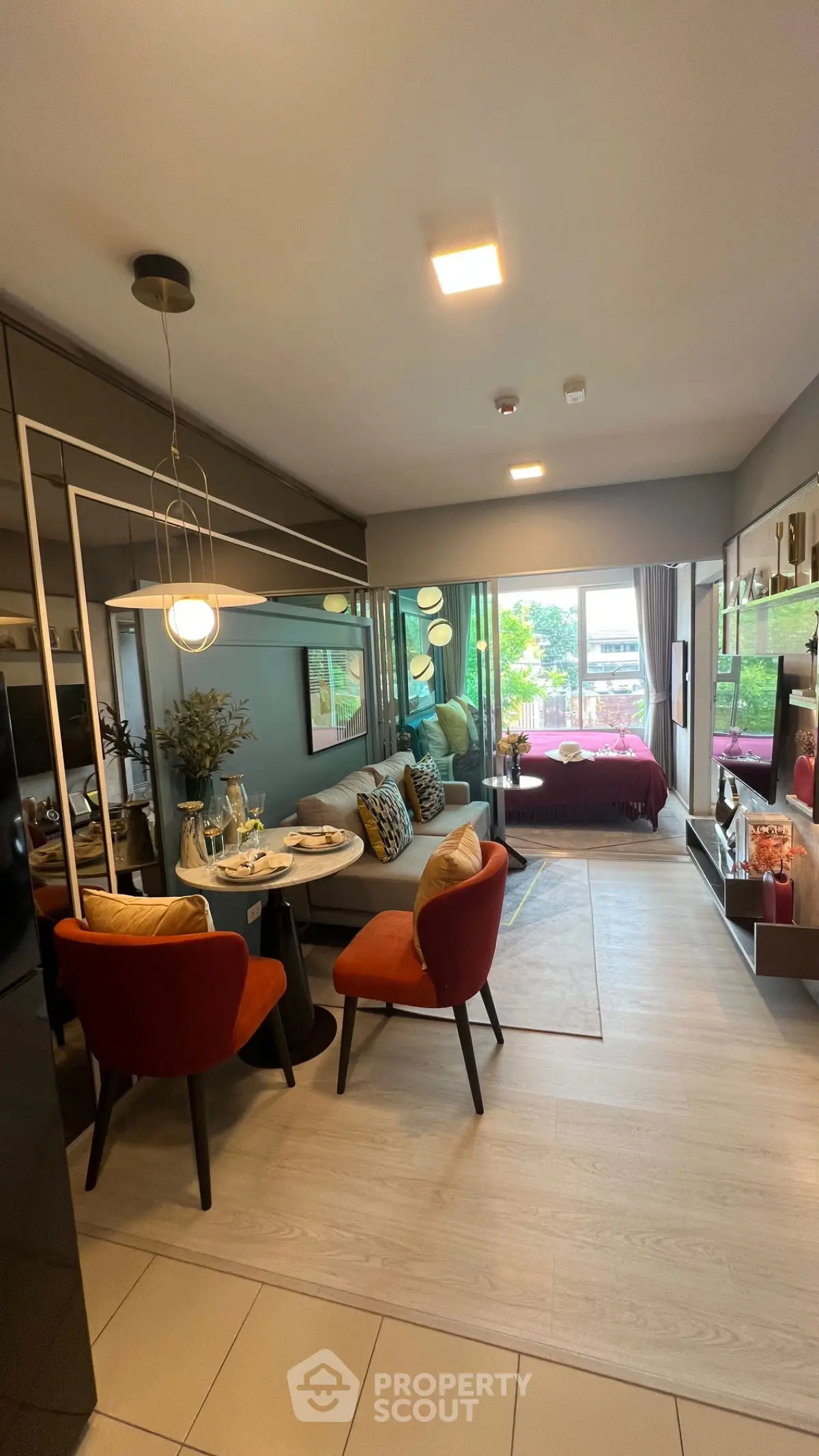 Modern open-plan living room with dining area and bedroom, featuring stylish decor and large windows.