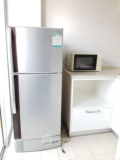 Modern kitchen with sleek refrigerator and microwave in bright, minimalist design.