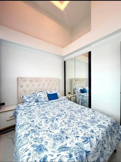 Charming bedroom with elegant decor and mirrored wardrobe in modern apartment.
