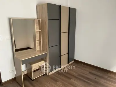 Modern bedroom with sleek wardrobe and stylish vanity set on wooden flooring.