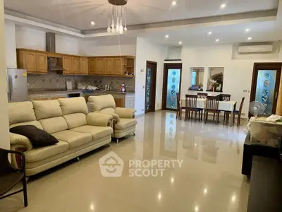 Spacious open-plan living and dining area with modern kitchen and elegant lighting.