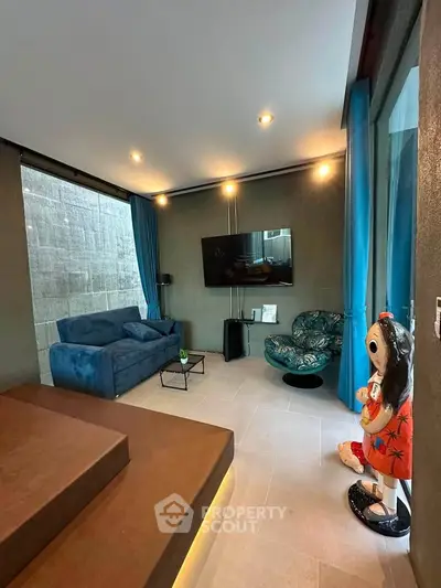 Modern living room with stylish decor and large TV, featuring cozy seating and unique art piece.
