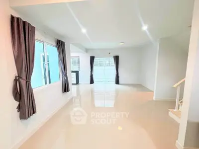 Spacious modern living room with large windows and sleek tile flooring.