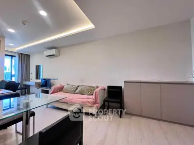 Modern living room with sleek furniture and ambient lighting, featuring a cozy sofa and glass dining table.