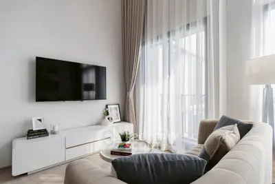 Modern living room with sleek design, featuring a cozy sofa, wall-mounted TV, and elegant sheer curtains.