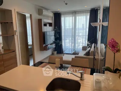 Modern living room with open kitchen, featuring large windows and stylish decor in a high-rise apartment.
