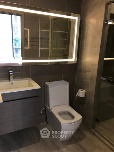 Modern bathroom with sleek fixtures and illuminated mirror in luxury apartment.